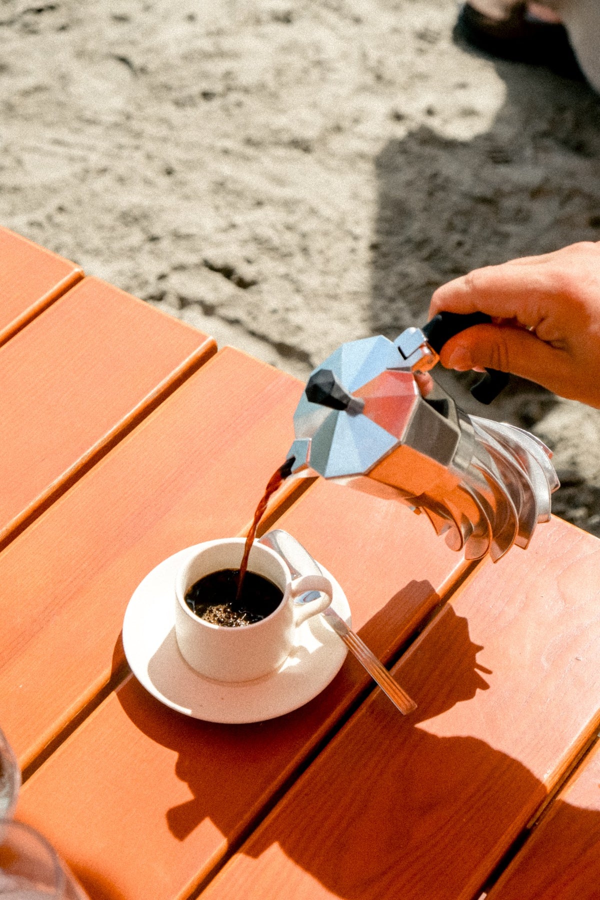 Close view of espresso being poured from the Turbo Moka 2-cup, turbine-finned base in the sun