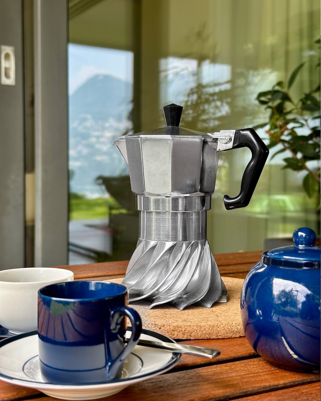 Turbo Moka on an outdoor breakfast table with blue ceramic cups and a mountain view behind