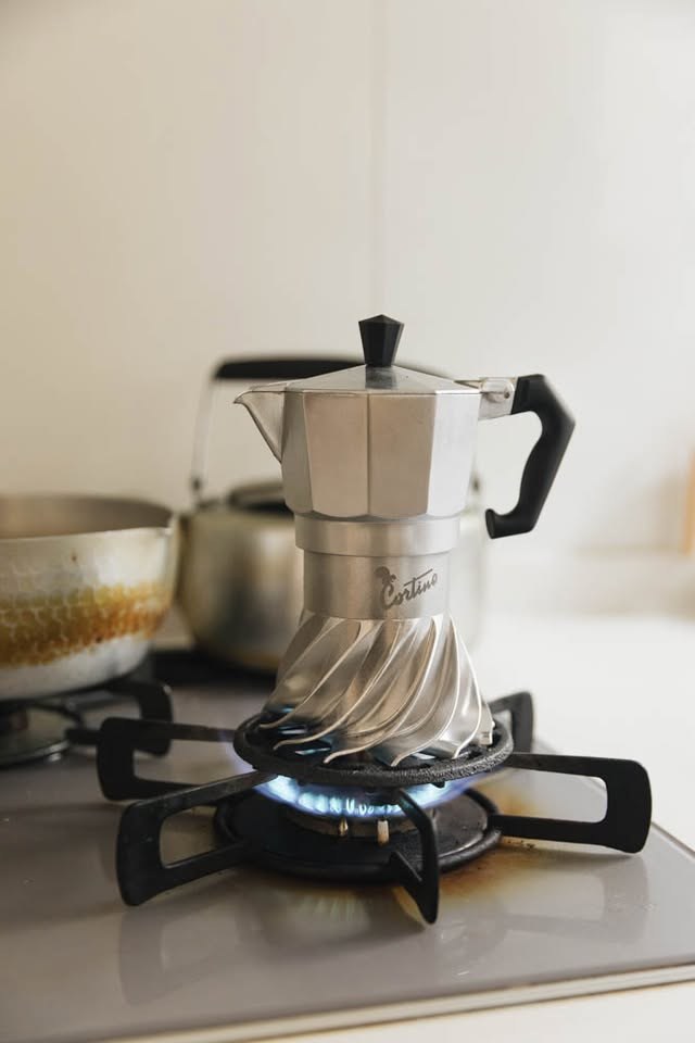 Turbo Moka Cortina Edition brewing on a gas stove, the blue flame wrapping around the finned base