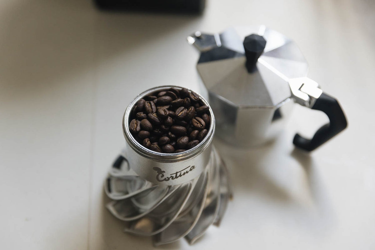 Turbo Moka Cortina Edition boiler filled with roasted coffee beans beside the aluminium moka top