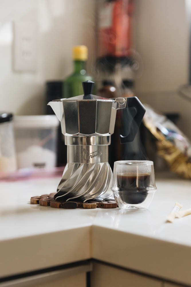 Turbo Moka Cortina Edition on a kitchen counter next to a glass of freshly brewed coffee