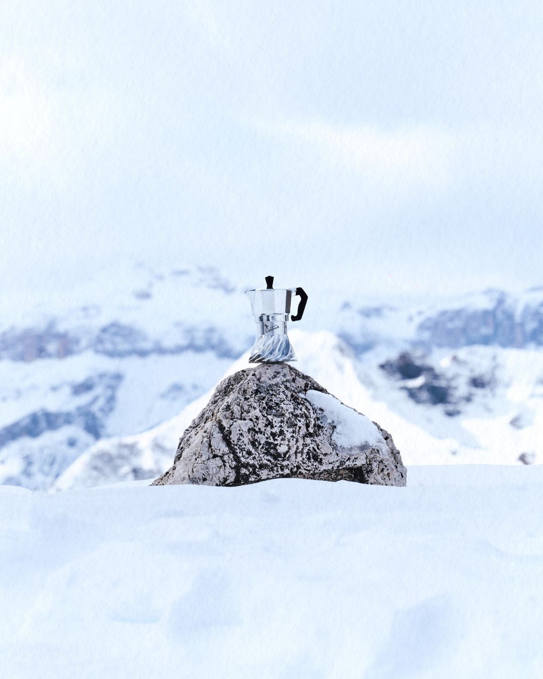 Turbo Moka Cortina Edition standing on a rock in deep snow, snow-covered Dolomite ridges in the distance