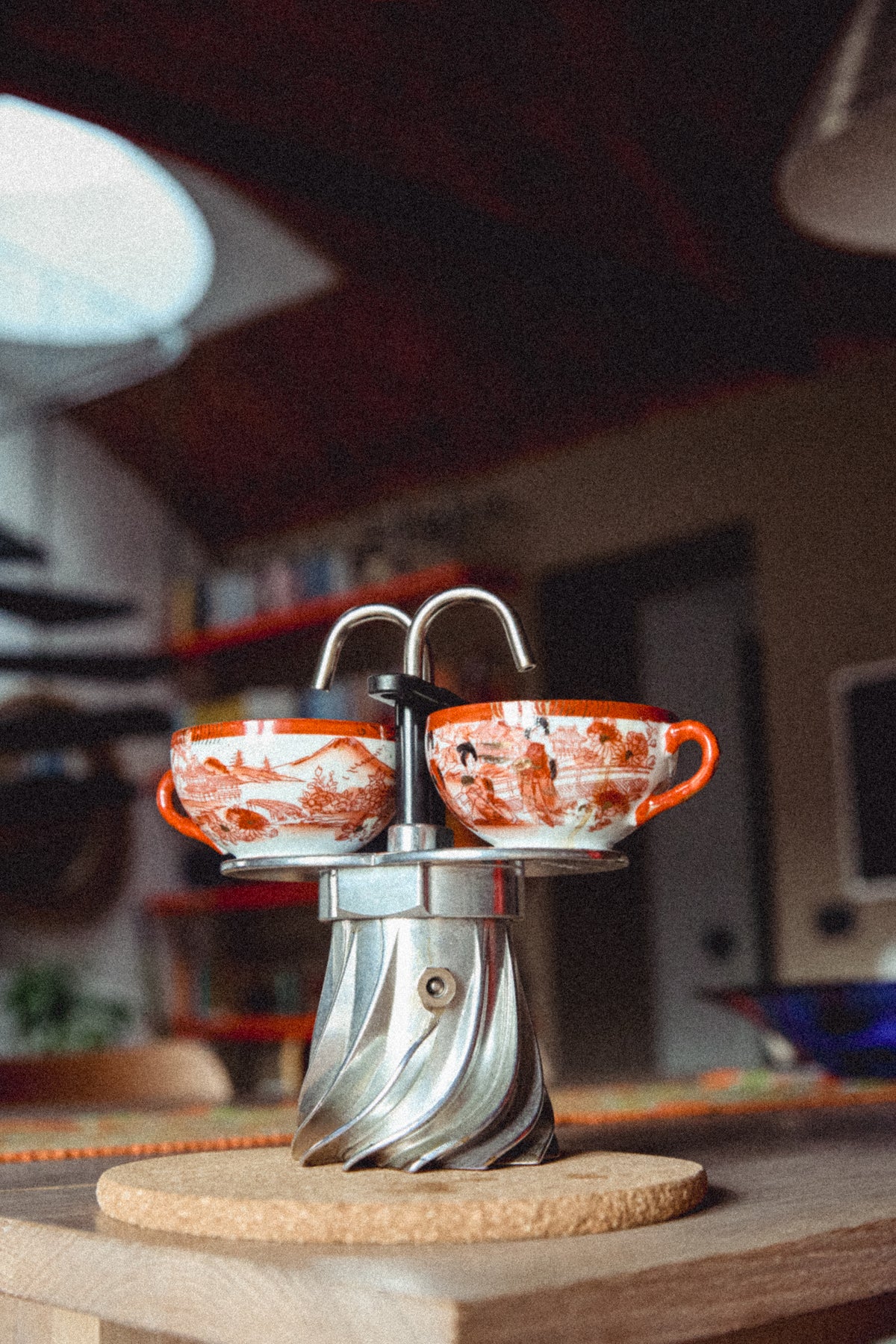 Turbo Moka Duetto twin-spout moka pot on a cork mat with two painted cups resting on its spouts