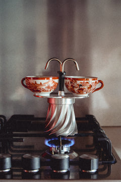 Turbo Moka Duetto brewing on a gas hob, coffee running through both spouts into two cups